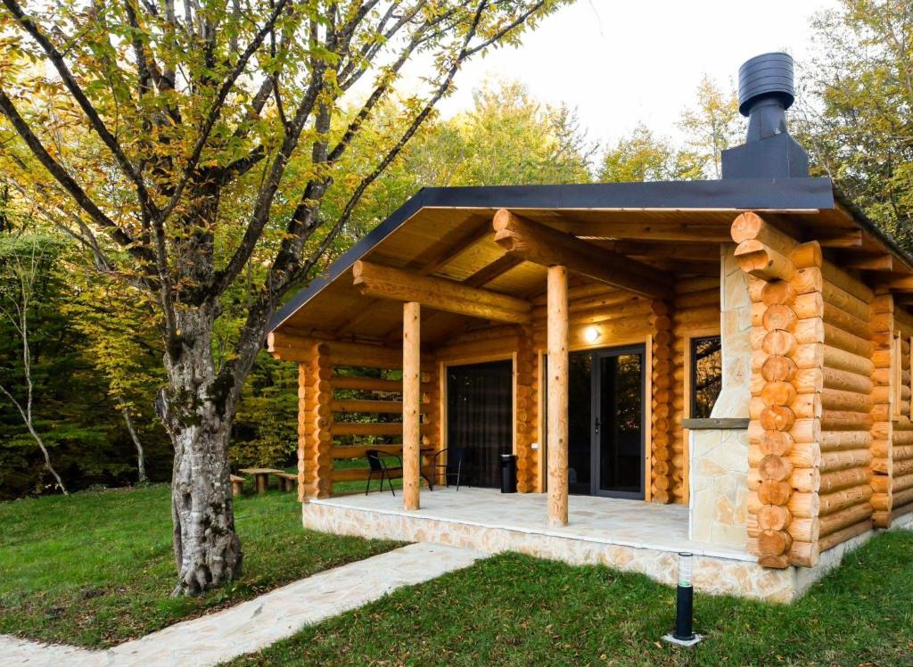a log cabin with a black roof and a fireplace at Buriani-resort in Tsʼkhvarichamia