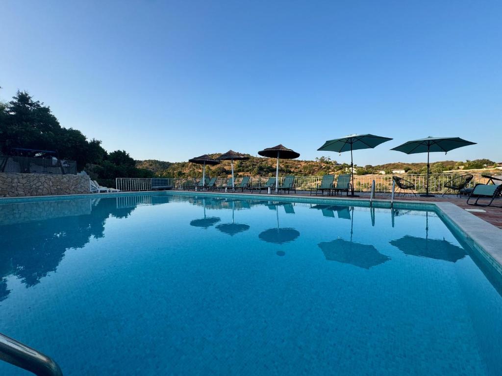 a large swimming pool with umbrellas and chairs at Herdade Da Corte in Tavira