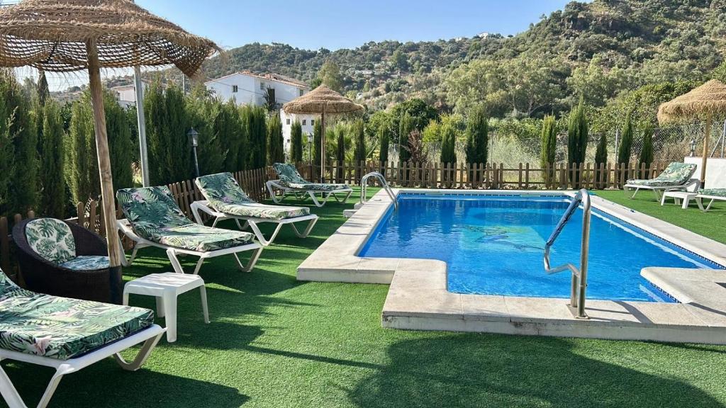 a swimming pool with chairs and an umbrella at Villa Andrea Comares in Comares