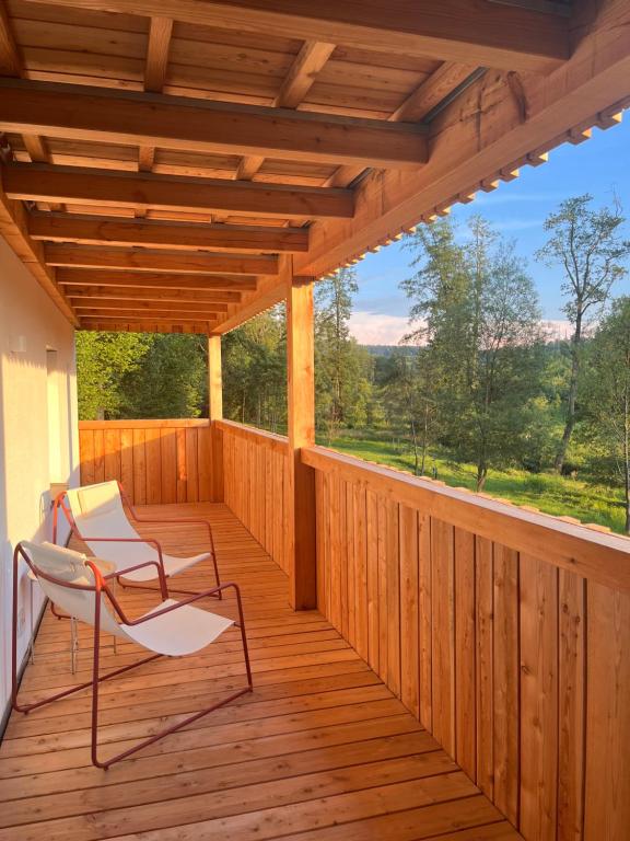 a wooden porch with two chairs on a deck at Mitteraubach in Jandelsbrunn