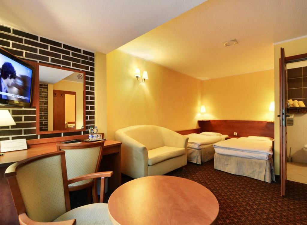 Pokój hotelowy z sypialnią z łóżkiem i biurkiem w obiekcie Hotel Astra Tajemniczy Ogród w Poznaniu