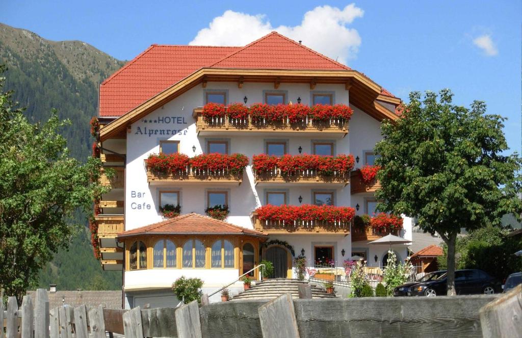 a large building with red flowers on the balconies at B&B Hotel Alpenrose Rooms & Apartments in Valles