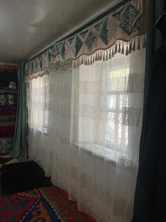 a window with white curtains in a room at Ademi Art in Kyzart