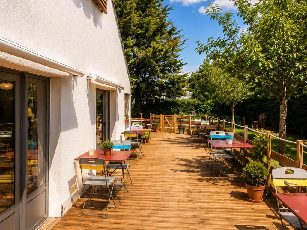 a row of tables and chairs on a wooden deck at Greet hôtel Saint-Nazaire-Trignac, Nouvelle marque du groupe Accor in Saint-Nazaire