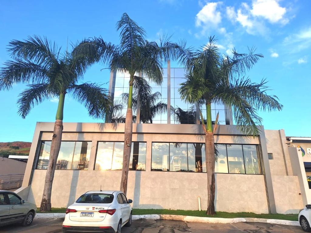 a building with palm trees in front of it at Hotel Planalto 2 in Governador Valadares