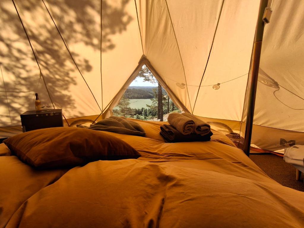 a bed in a tent with a large window at Halden Glamping in Halden