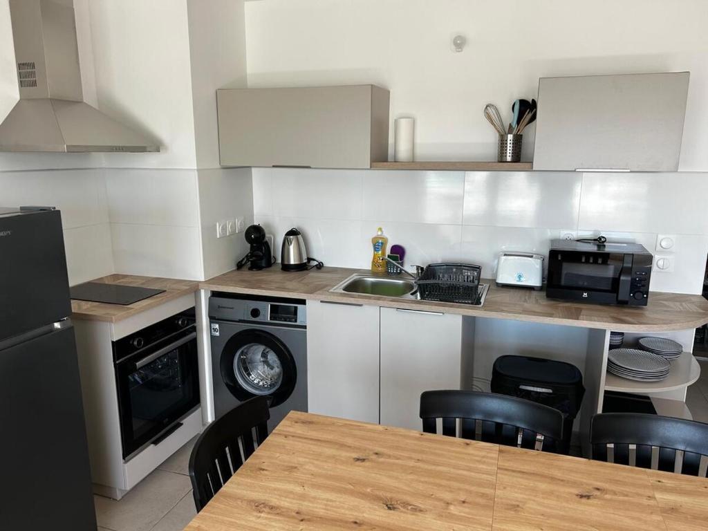 a kitchen with a sink and a table with chairs at La Kaz Saint-Annaise in Sainte-Anne