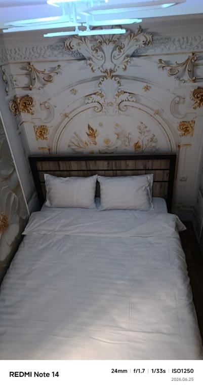 a bedroom with a white bed with a wall at Апартаменты in Jermuk