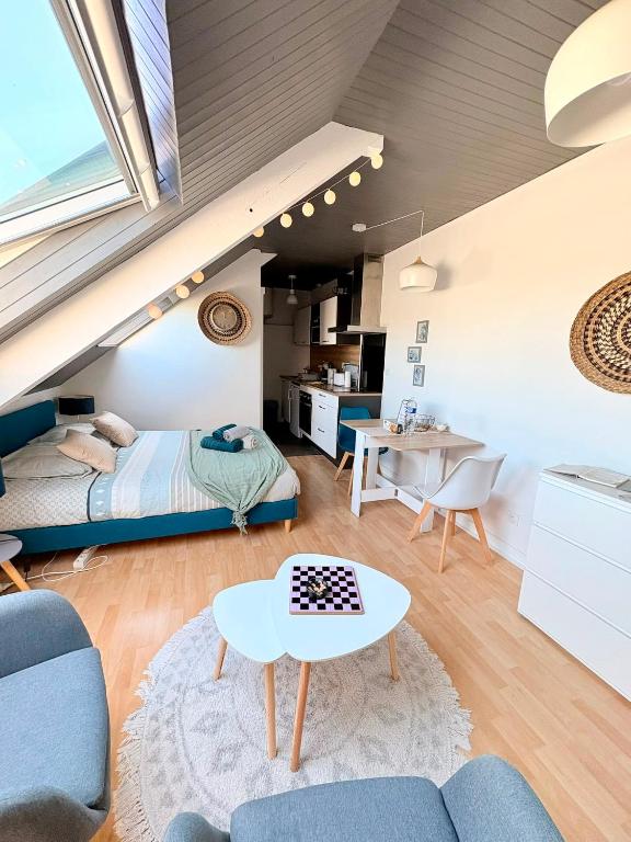 a bedroom and living room with a bed and a table at L'Odyssée - Studio cosy avec vue mer - Lumineux - Parking - Wifi in Pléneuf-Val-André