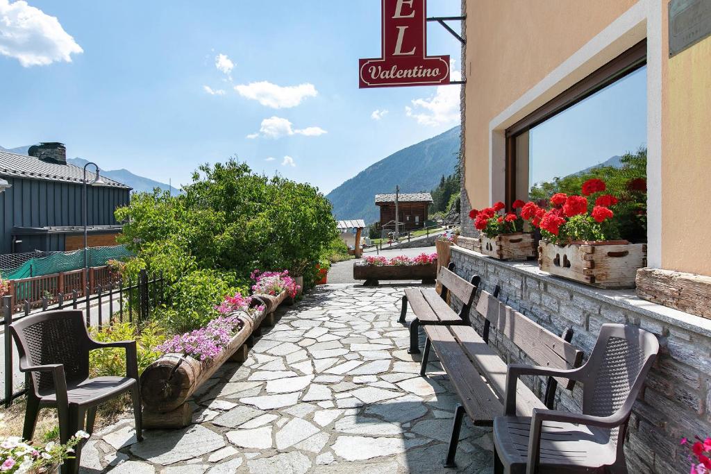 a row of benches outside of a building with flowers at Hotel Valentino - Bionaz in Bionaz