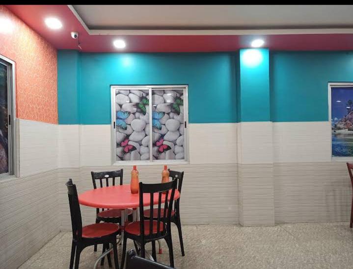 a dining room with a red table and chairs at Shravan Hotel in Rāmgarh