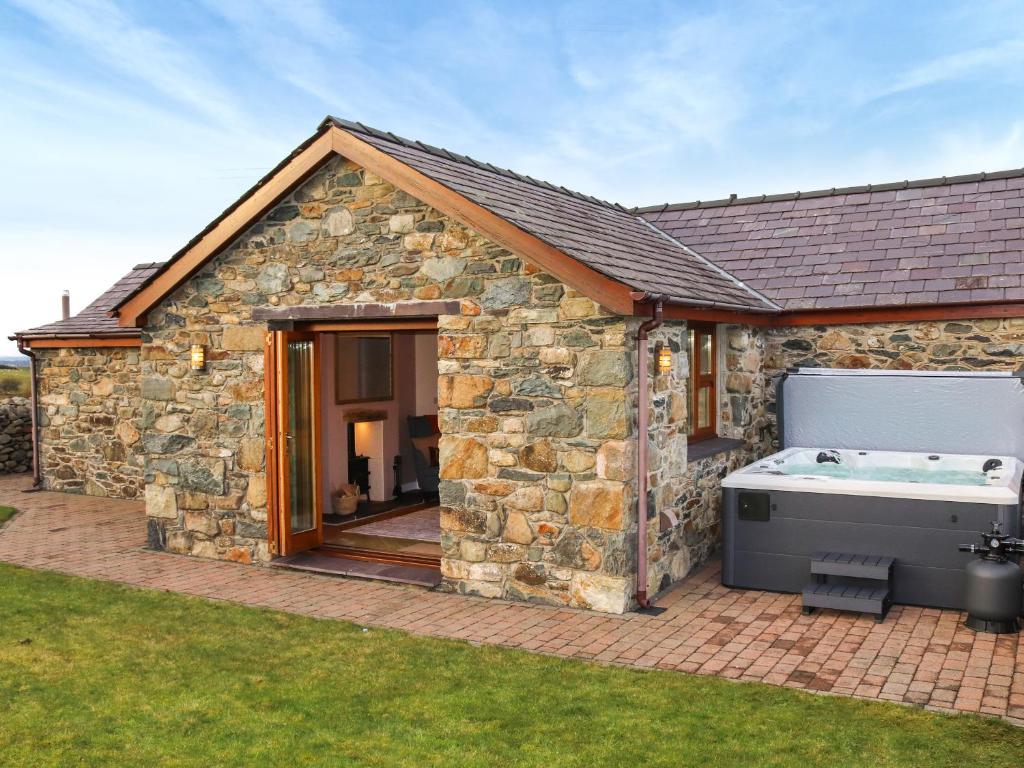 a stone house with a hot tub in the yard at Beudy Newydd - Uk50959 in Llanllechid