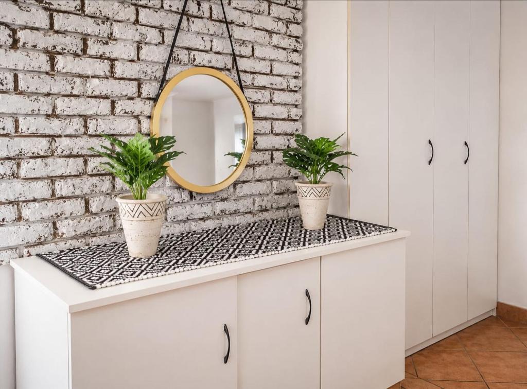 a bathroom with white cabinets and two potted plants at Anna Boeremeisie Guesthouse in Benoni