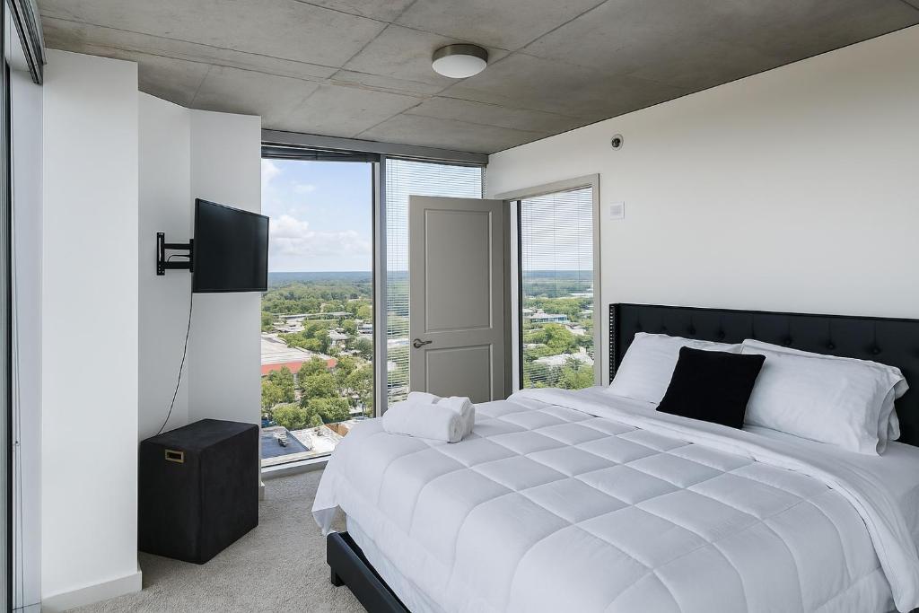 a bedroom with a large white bed with a large window at Condo in downtown oak city highrise in Raleigh