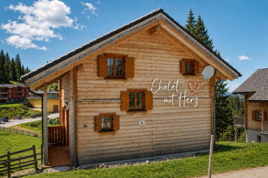 a log house with a sign on the side at Feriendorf Koralpe Chalet Almrausch in St. Gertraud