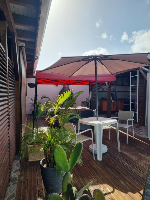 a patio with a table and an umbrella on a deck at Charmant studio d'invité - Baie-Mahault in Baie-Mahault