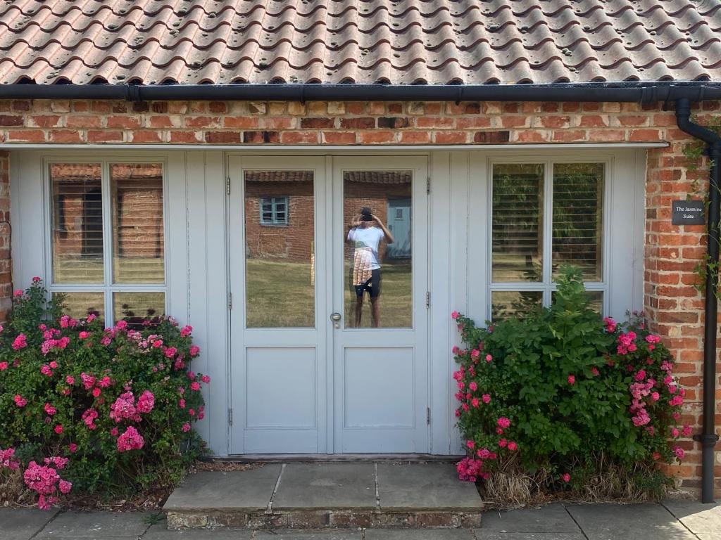 a woman is standing in the reflection of a door at Lavender Cottage in Long Bennington