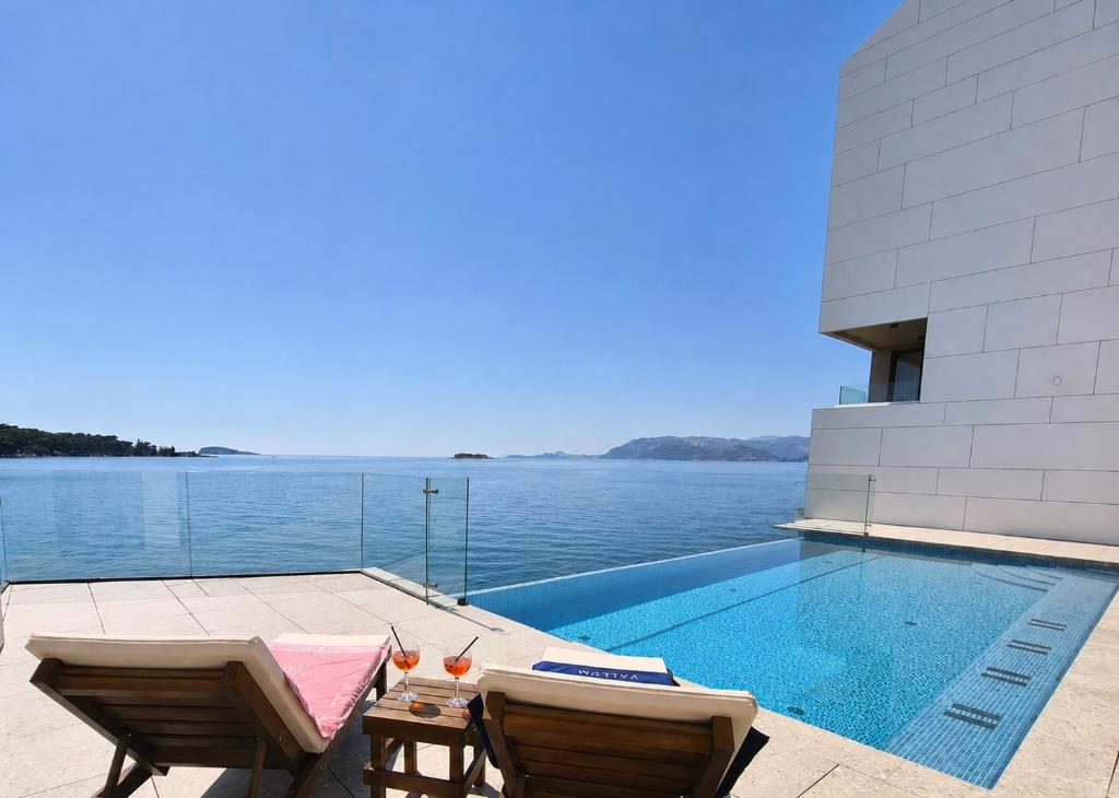 ein Pool mit zwei Stühlen und einem Tisch neben dem Wasser in der Unterkunft Hotel Vallum by St Pietro in Cavtat
