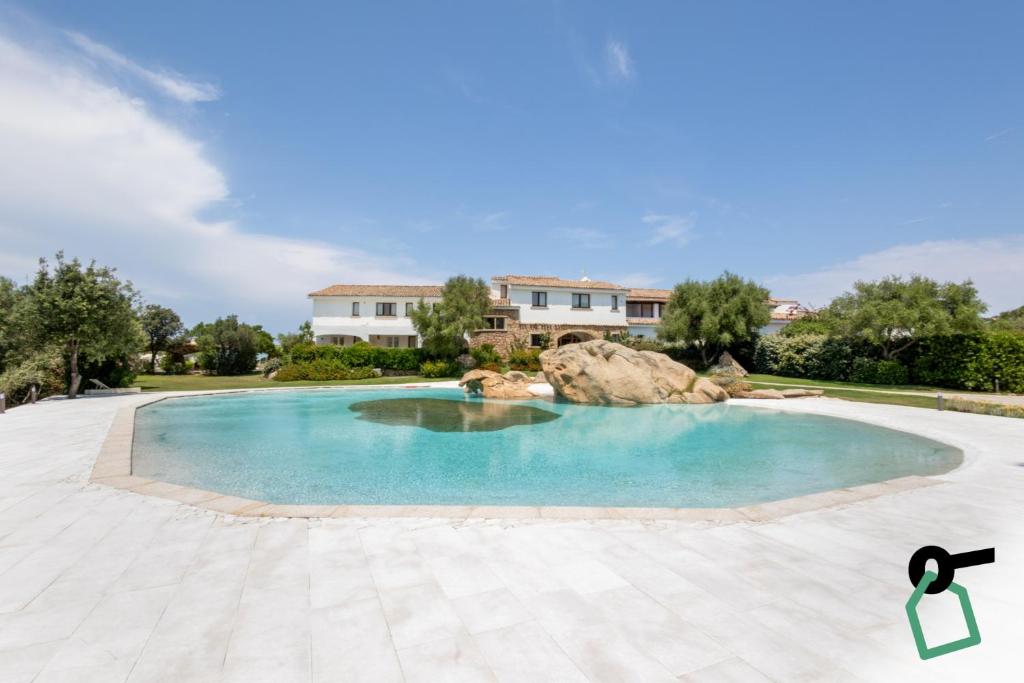 a swimming pool in a yard with a house in the background at Hotiday Baja Sardinia Saline in Baja Sardinia