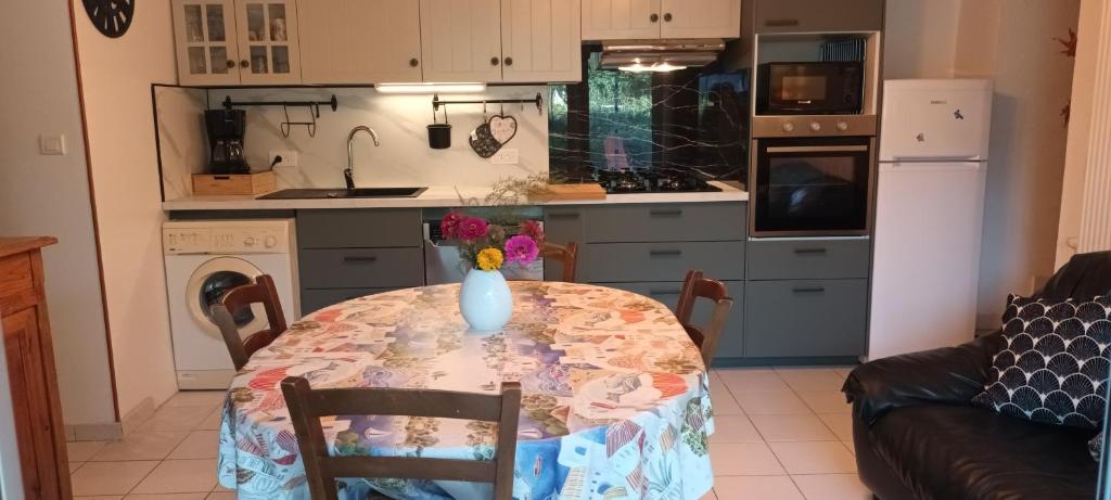 a kitchen with a table with a vase on it at La glycine in Sahune