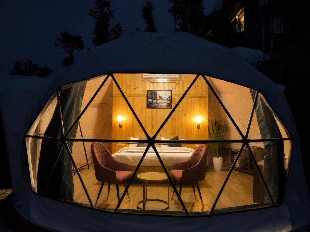 a tent with two chairs and a table in it at Glamp by Edge Resort Premium Luxury Domes with Mountain Views in Mussoorie