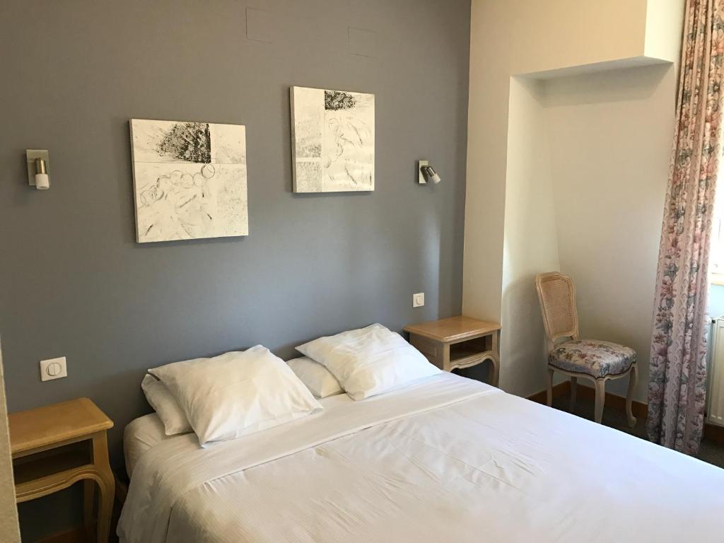sypialnia z białym łóżkiem i krzesłem w obiekcie Hôtel du Rangen w mieście Thann