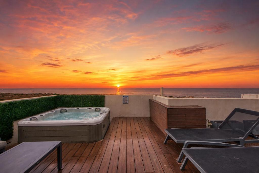 a hot tub on a deck with the sunset at Heated Private Jacuzzi Penthouse Breathtaking Seaview in Pembroke