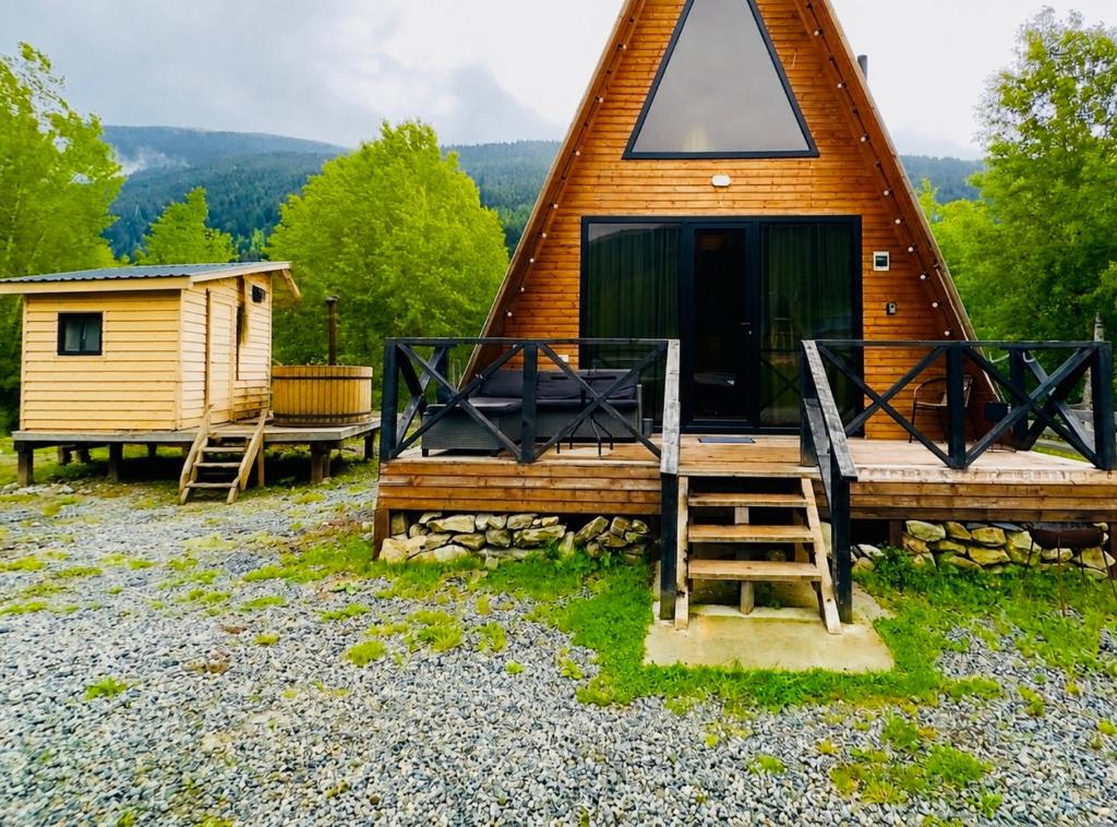 a cabin with a thatched roof and a staircase to the front at Cottage and sauna hill silence mestia 2 in Mestia
