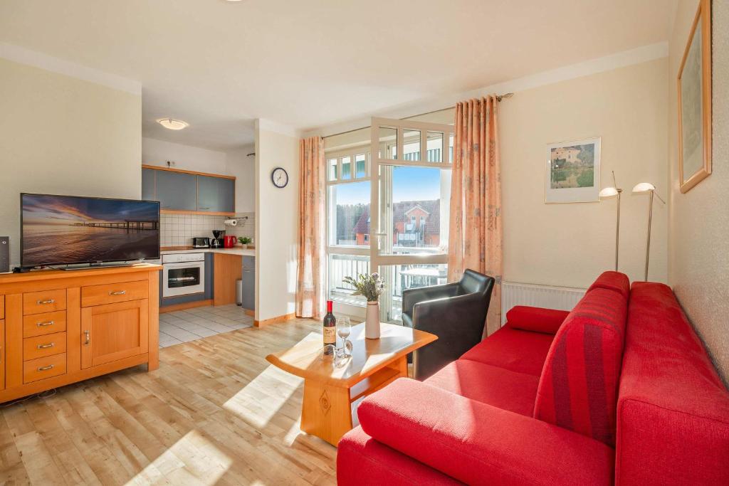 a living room with a red couch and a television at Ferienwohnung Koralle in Koserow
