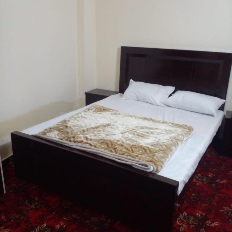 a large bed in a room with a black frame at UK Residencia in Murree