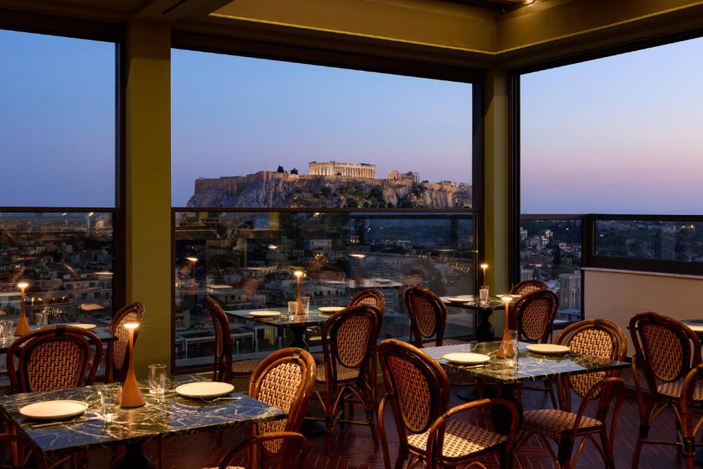 a restaurant with tables and chairs and a view of the city at Astor Hotel Athens in Athens