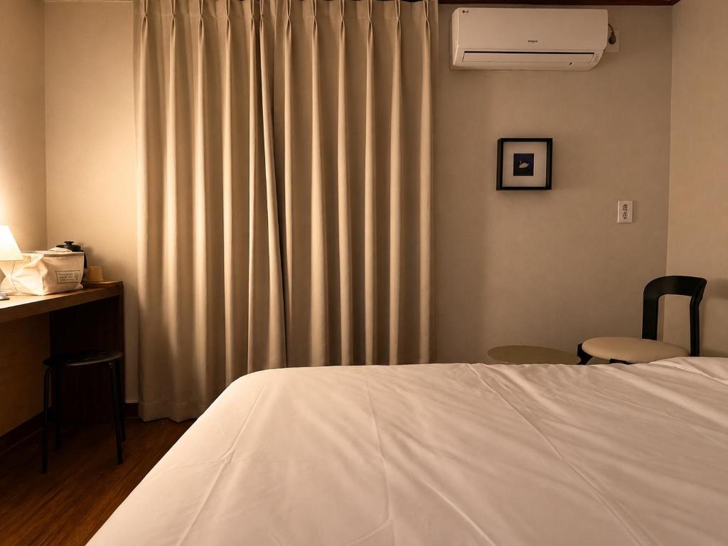 a bedroom with a bed and a desk and a window at Stay PAUSE in Bucheon