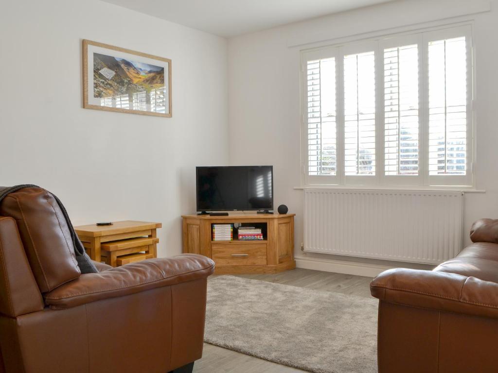 a living room with two chairs and a flat screen tv at Wise Cottage in Keswick