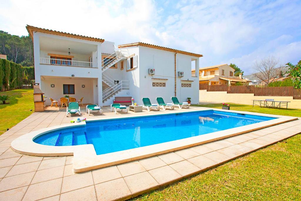 a villa with a swimming pool in front of a house at Villa Can Tomas in Port de Pollensa