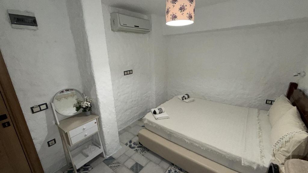 a small white bedroom with a bed and a mirror at Afet inn in Çeşme