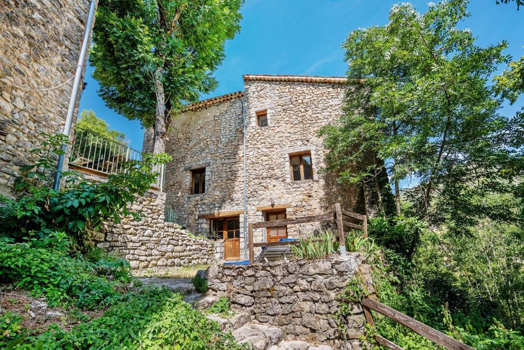 an exterior view of a stone house with trees at Studio La Chambrette in Blieux