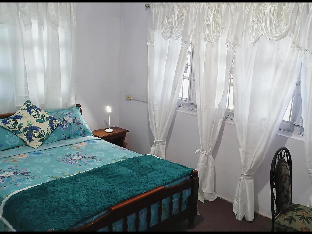a bedroom with white curtains and a bed and a window at Gazebo in Port-of-Spain
