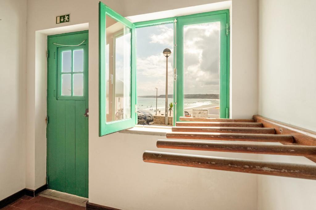 a stairway with a green door and a view of the beach at Balili Surf House in Baleal