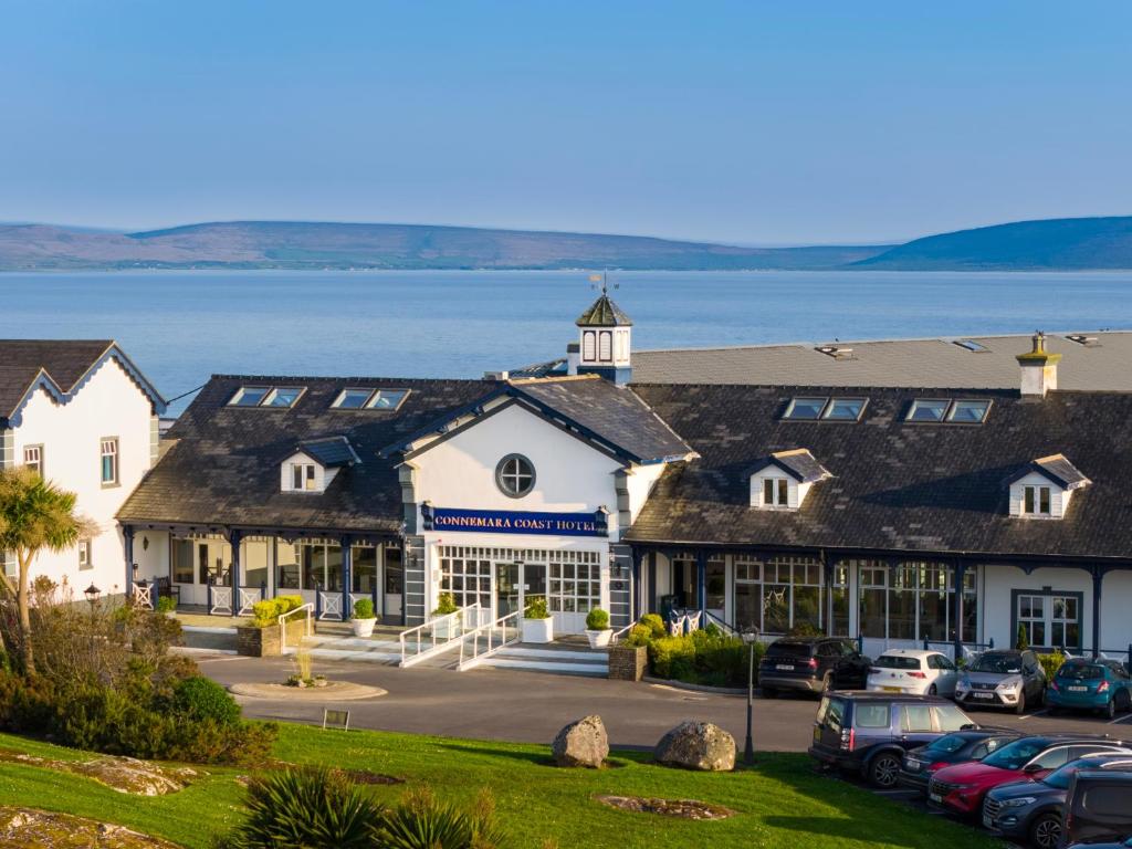 a row of buildings with cars parked in a parking lot at Connemara Coast Hotel in Furbo