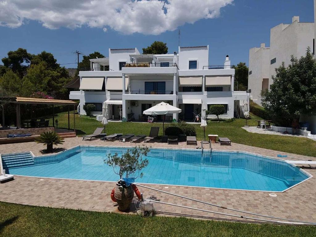 a large house with a swimming pool in front of it at Kinetious Nisous Stylish Apt, Pool, near the Beach in Kineta