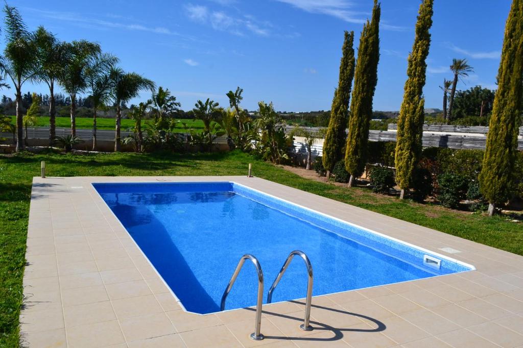 una piscina azul en un patio con árboles en Villa Aris, en Ayios Theodhoros