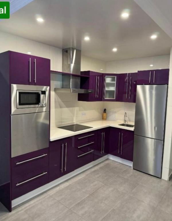 a kitchen with purple cabinets and a stainless steel refrigerator at Apartamento Corralejo in Corralejo