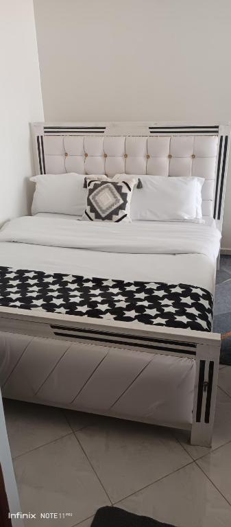 a bed with a black and white comforter and pillows at Studio BNB Meru town CBD in Meru