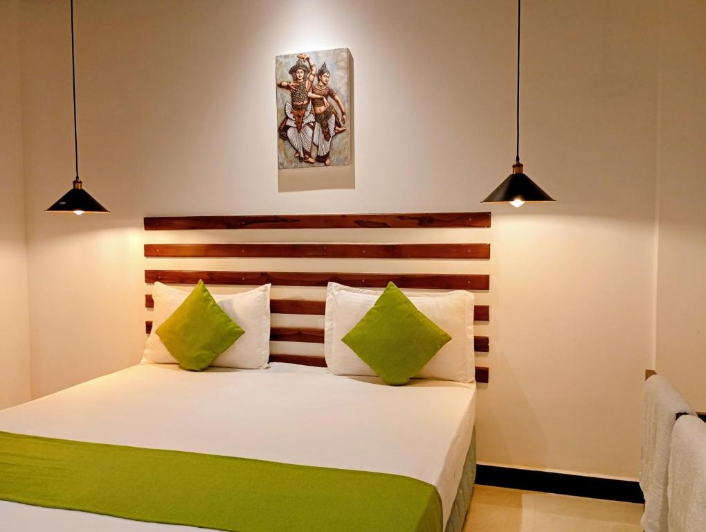 a bedroom with a bed with green and white pillows at Thisara Guest House in Polonnaruwa