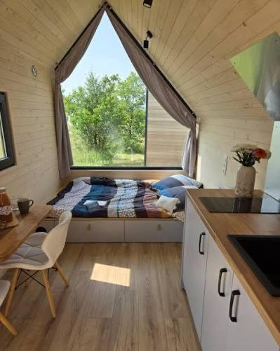 ein kleines Schlafzimmer mit einem Bett und einem großen Fenster in der Unterkunft Tiny House in Weismes