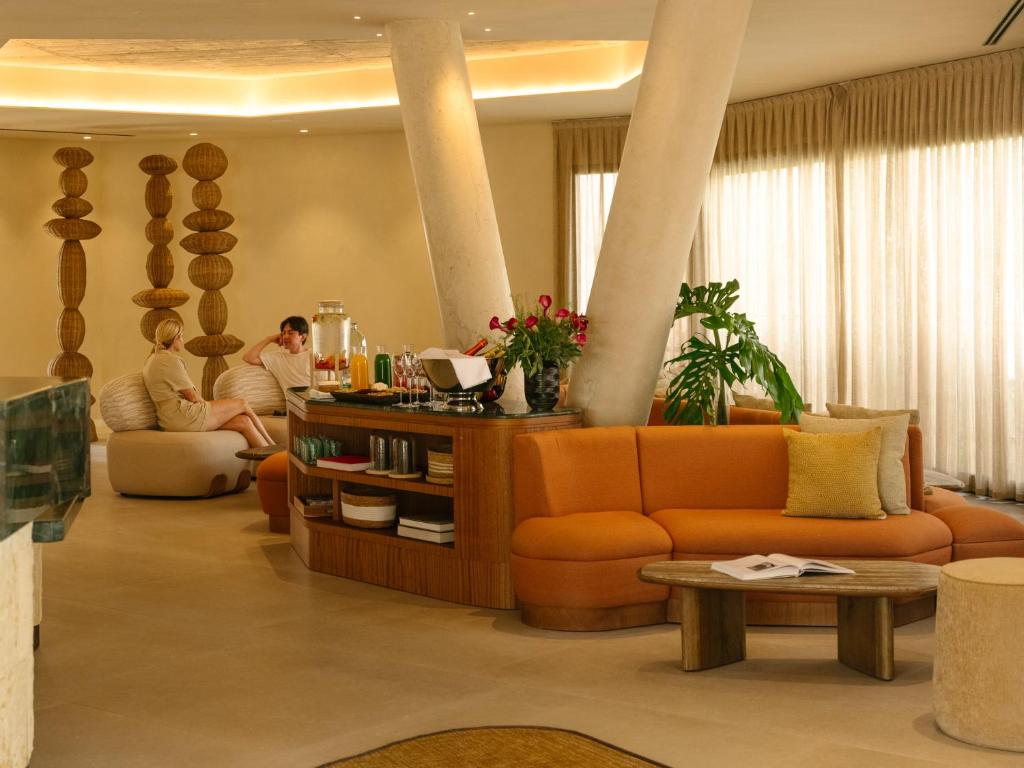 a living room with an orange couch and two people at RIVELIAN Grand Menorca in Menorca