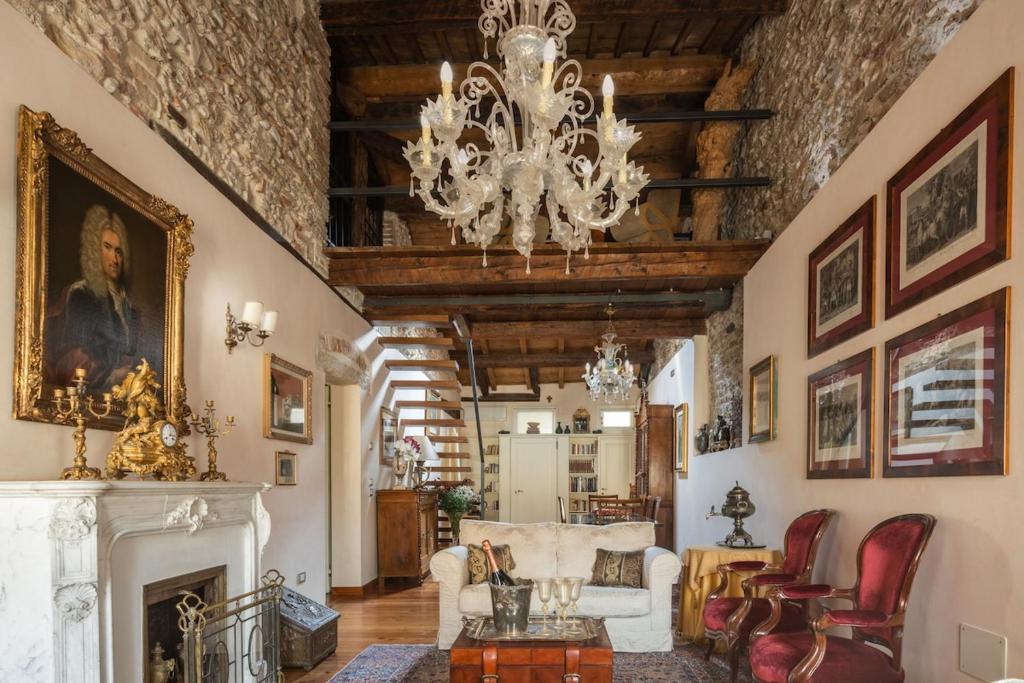 a living room with a chandelier and a fireplace at Palazzo Benassi Penthouse nel cuore di Asolo in Asolo