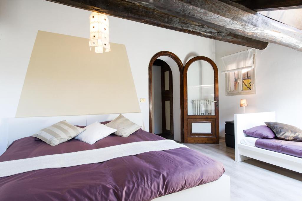 a white bedroom with a purple bed and a mirror at Lo Chalet di Trastevere in Rome