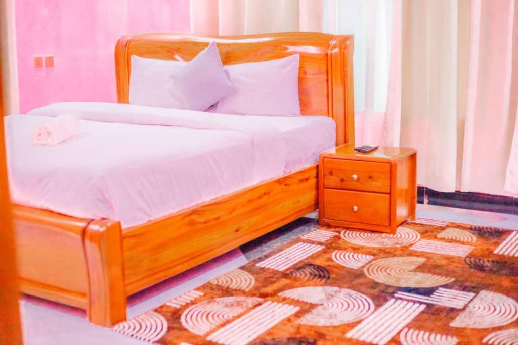 a bedroom with a wooden bed with a night stand at MIAMi VILLA HOTEL in Mpanda