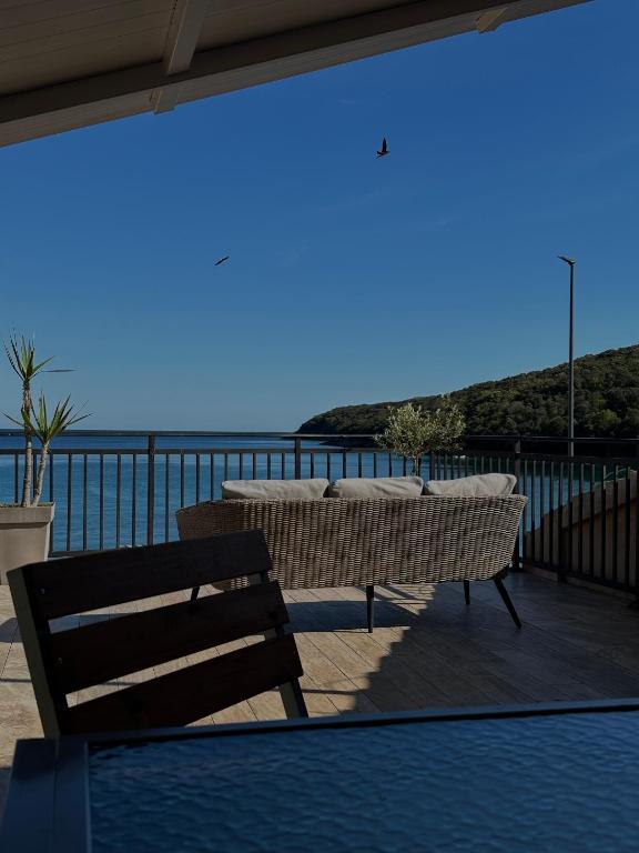 a patio with a table and a bench and the ocean at Apartments Boss in Budva